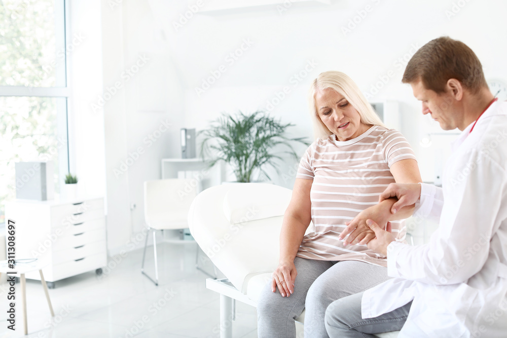 Doctor examining mature woman with joint pain in clinic Doctor examining mature woman with joint pain in clinic