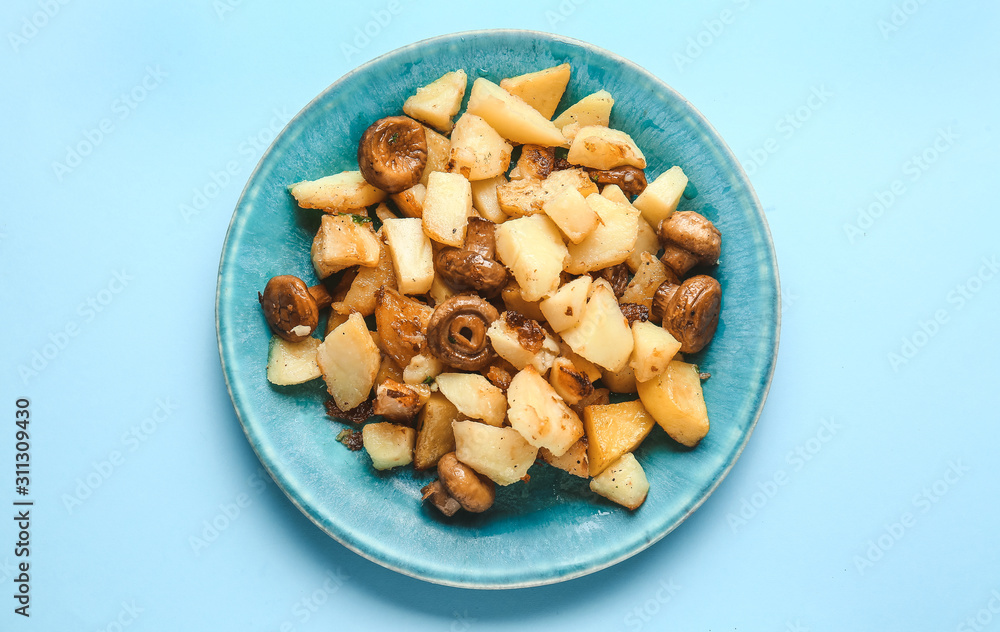 Plate with tasty cooked mushrooms and potato on color background Plate with tasty cooked mushrooms and potato on color background