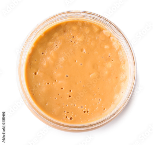 Tasty peanut butter in jar on white background, top view