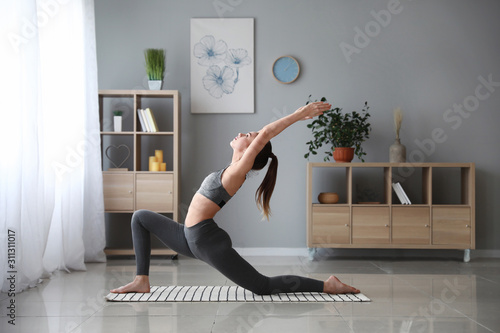 Fototapeta Naklejka Na Ścianę i Meble -  Beautiful young woman practicing yoga at home