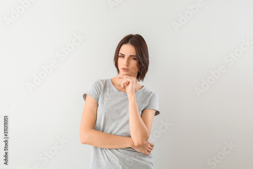Beautiful thoughtful young woman on grey background © Pixel-Shot