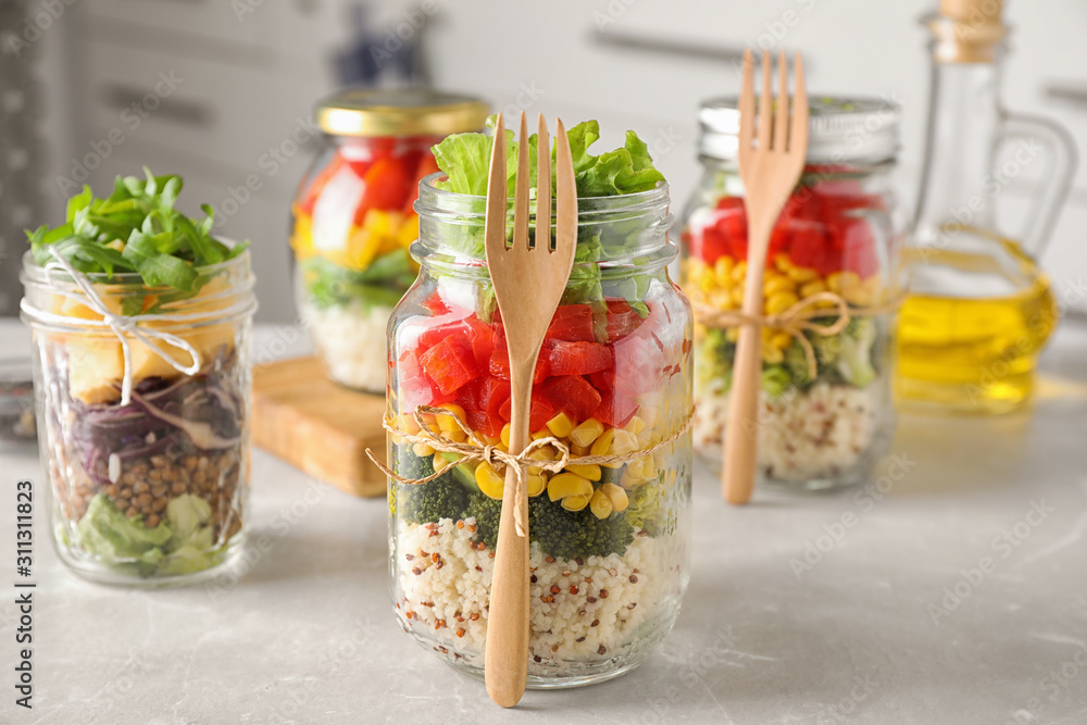 Glass jars with healthy meal on light grey marble table Glass jars with healthy meal on light grey marble table