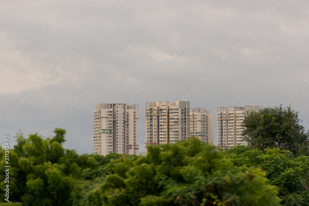 Skyscrapers behind line of trees with cloudy sky in Chennai, former Madras, in South India