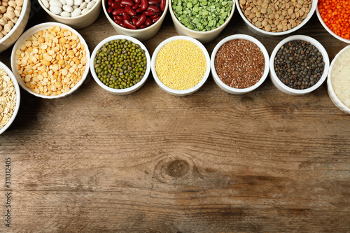 Different grains and cereals on wooden table, flat lay. Space for text