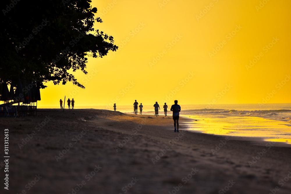 silhouette of people walking on the beach at sunset