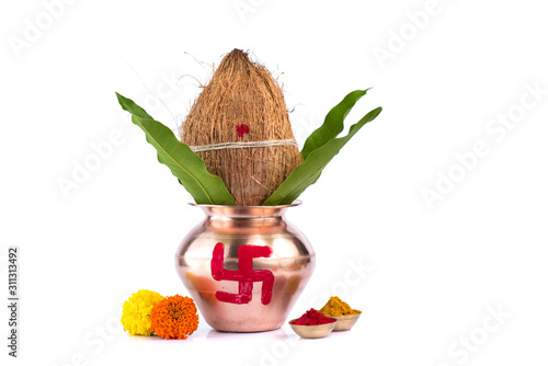 Copper Kalash with coconut, mango leaf, Haldi, kumkum and sweets with marigold flower decoration on a white background. Essential in Hindu puja.