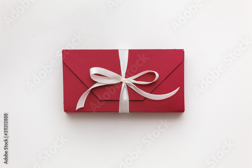 red gift box with white bow on a white background close-up