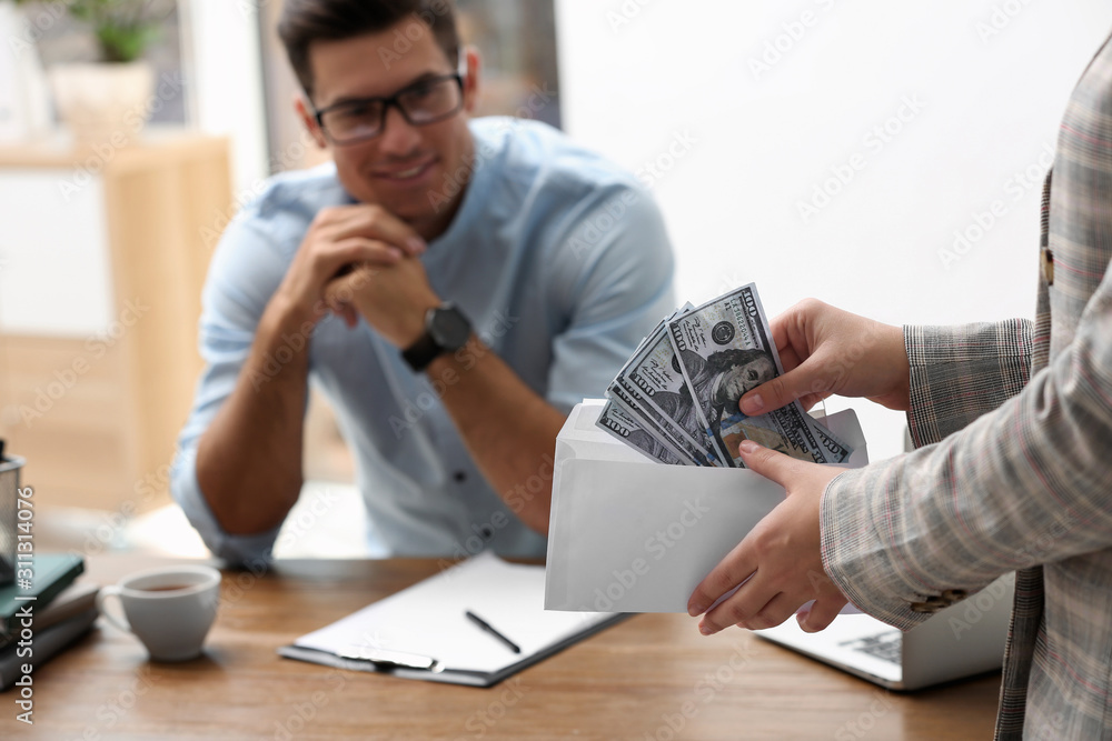 Woman offering bribe money to man at table, closeup Woman offering bribe money to man at table, closeup