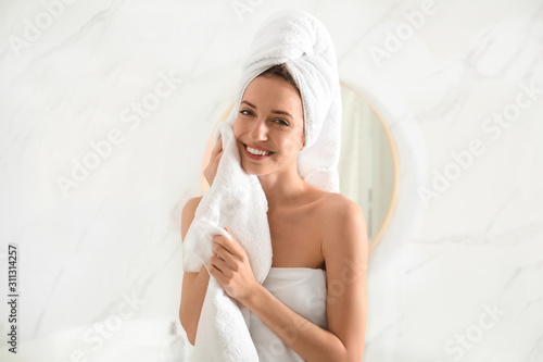 Vászonkép Young woman wiping face with towel in bathroom