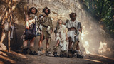 Tribe of Four Hunter-Gatherers Wearing Animal Skin Holding Stone Tipped Tools, Pose at the Entrance of their Cave. Portrait of Two Grown Male and Two Female Neanderthals and their Way of Living
