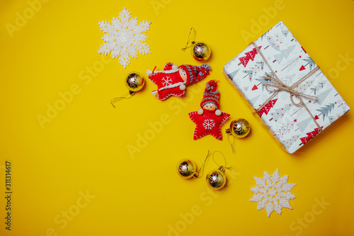 Orange christmas card with toy red knitted christmas stars in funny hats and white gift boxes. Christmas flat lay on the orange background with copy space.