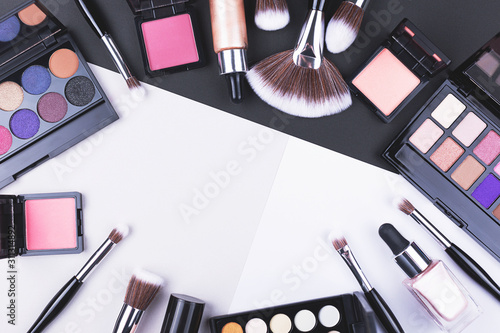 Creative beauty and makeup flat lay made with brushes, foundation, eye shadows and blush.