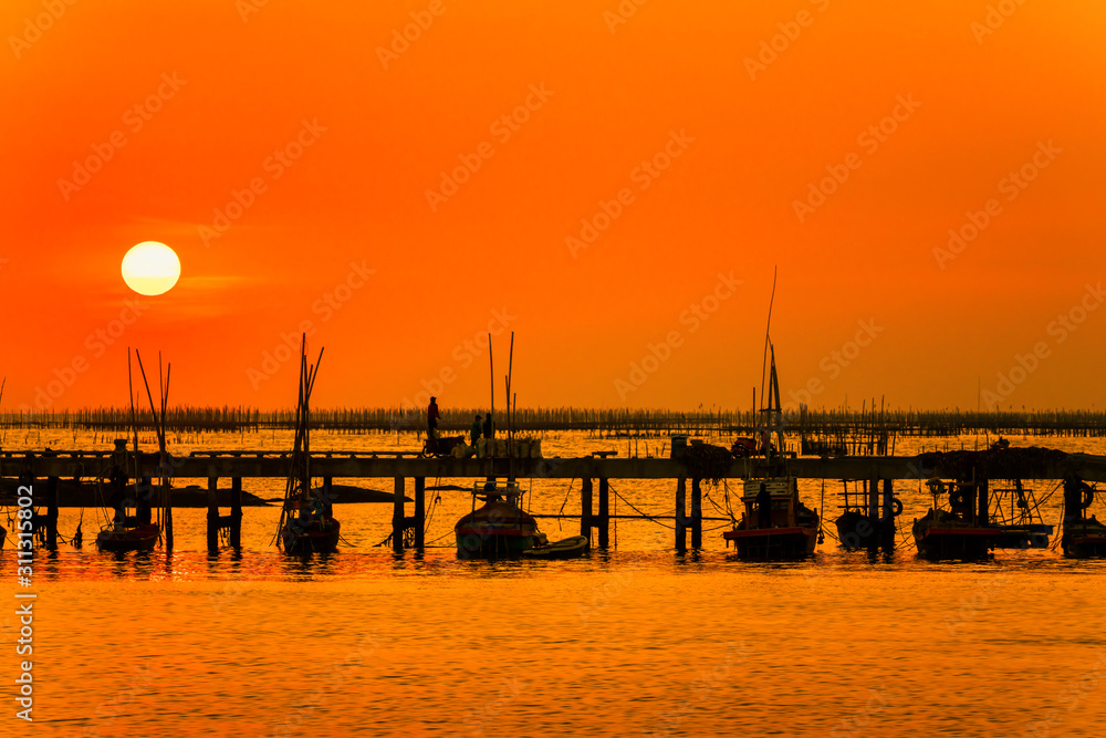 Fototapeta premium silhouette sunset at the sea. The way of life of fishermen on the bridge or jetty and returning from fishing from the sea. Chonburi, Thailand 22 Dec 2019.