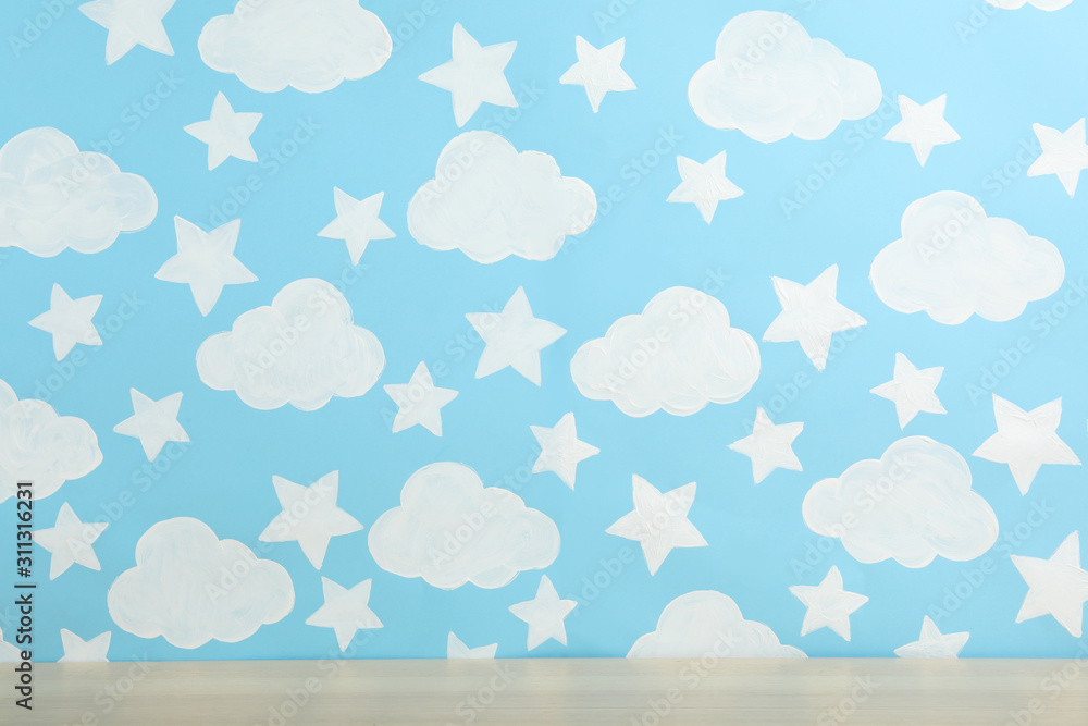 Wooden table near wall with painted blue sky. Idea for baby room interior Wooden table near wall with painted blue sky. Idea for baby room interior