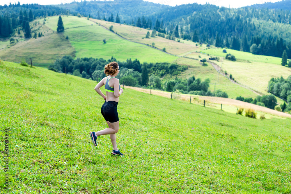 Healthy lifestyle woman trail runner running on mountain peak.