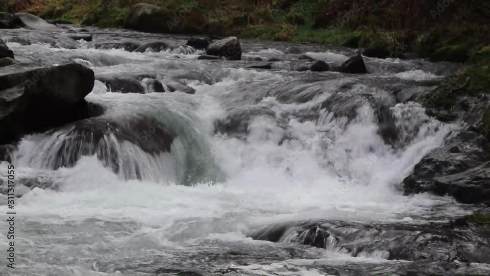 Torbid grey water of the river that flows between the stones caused by the melting snow in high mountains. Concept of melting glaciers, caused by climate change. Soft focus, close up footage. Torbid grey water of the river that flows between the stones caused by the melting snow in high mountains. Concept of melting glaciers, caused by climate change. Soft focus, close up footage.