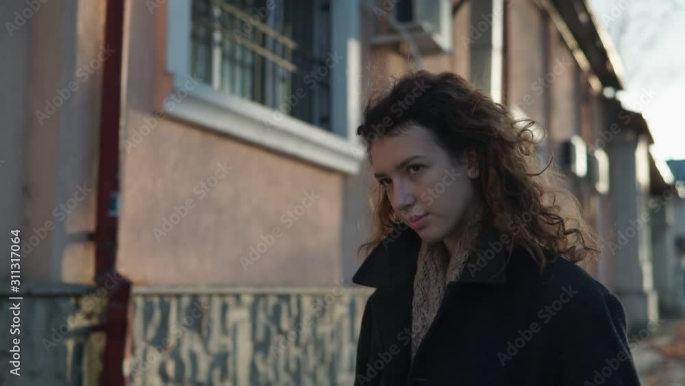 Dreaming young woman with spectacular curly red ginger hair looking at camera posing outdoor in downtown street. Female portrait. Dreaming young woman with spectacular curly red ginger hair looking at camera posing outdoor in downtown street. Female portrait.