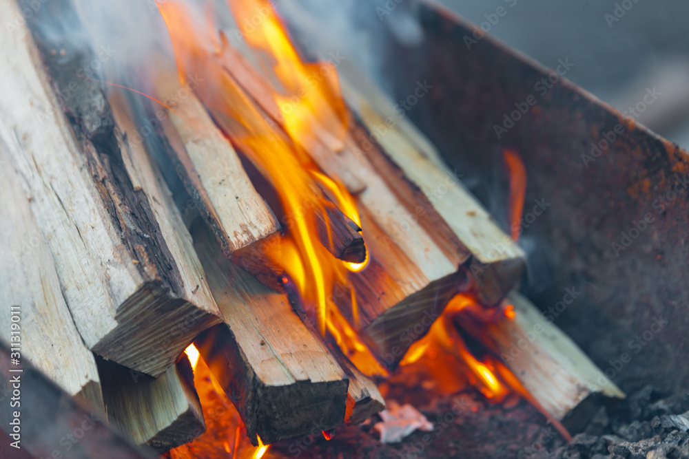 Fototapeta premium Burning logs for kindling a fire, flame and smoke on fire. Logs in a barbecue for frying meat.