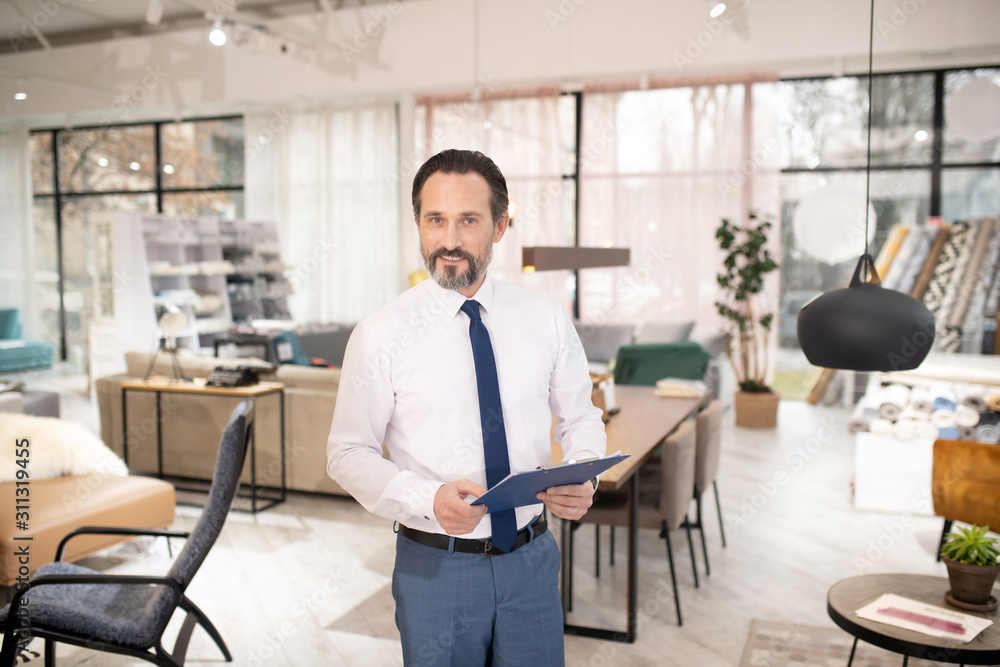 Furniture designer in tie and white shirt holding drawing ih his hands Furniture designer in tie and white shirt holding drawing ih his hands