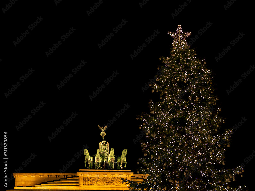 Illuminated Neoclassical Brandenburg Gate (Brandenburger Tor) and Christmas Tree in the year 2019 as viewed from the Pariser Platz, Berlin, Germany