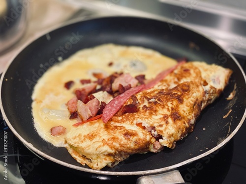 omelet with bacon and salami fried in a pan