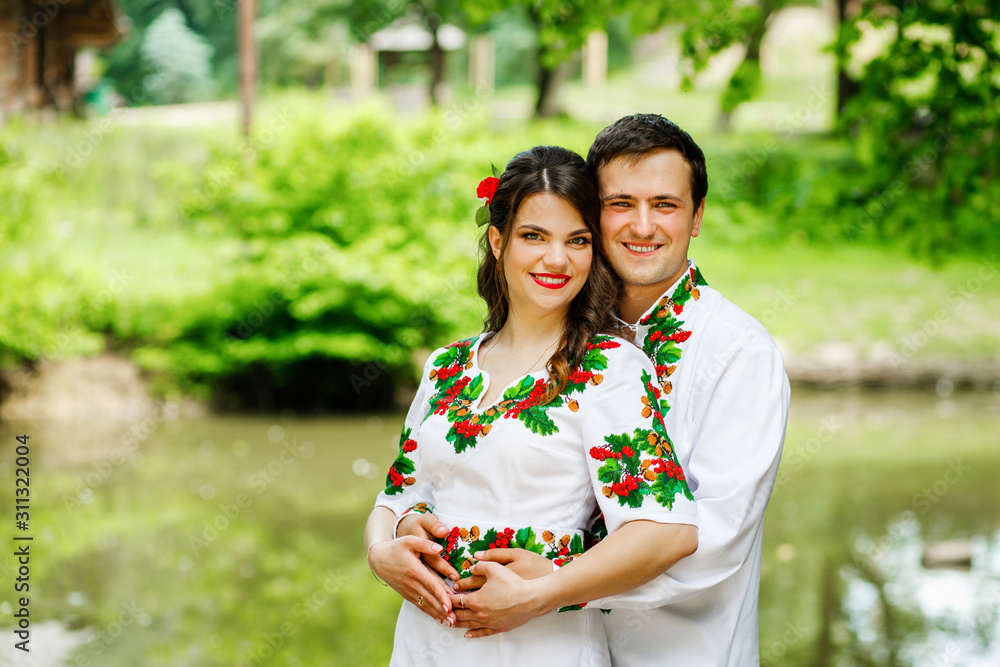Amazing couple in national costumes hugging near the lake Amazing couple in national costumes hugging near the lake