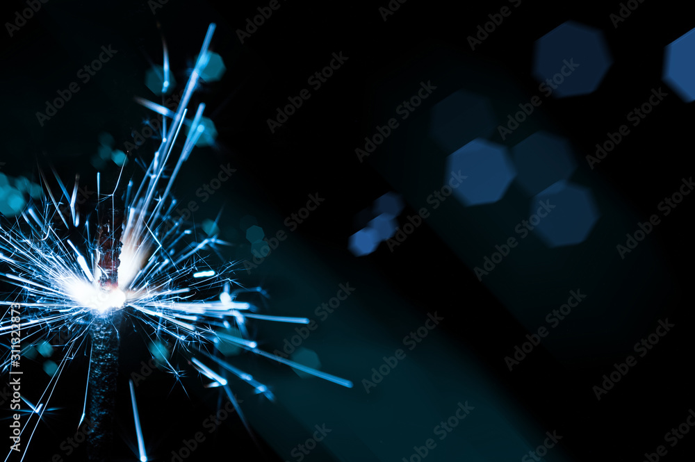 Obraz premium Sparkler in blue and white light on a black background