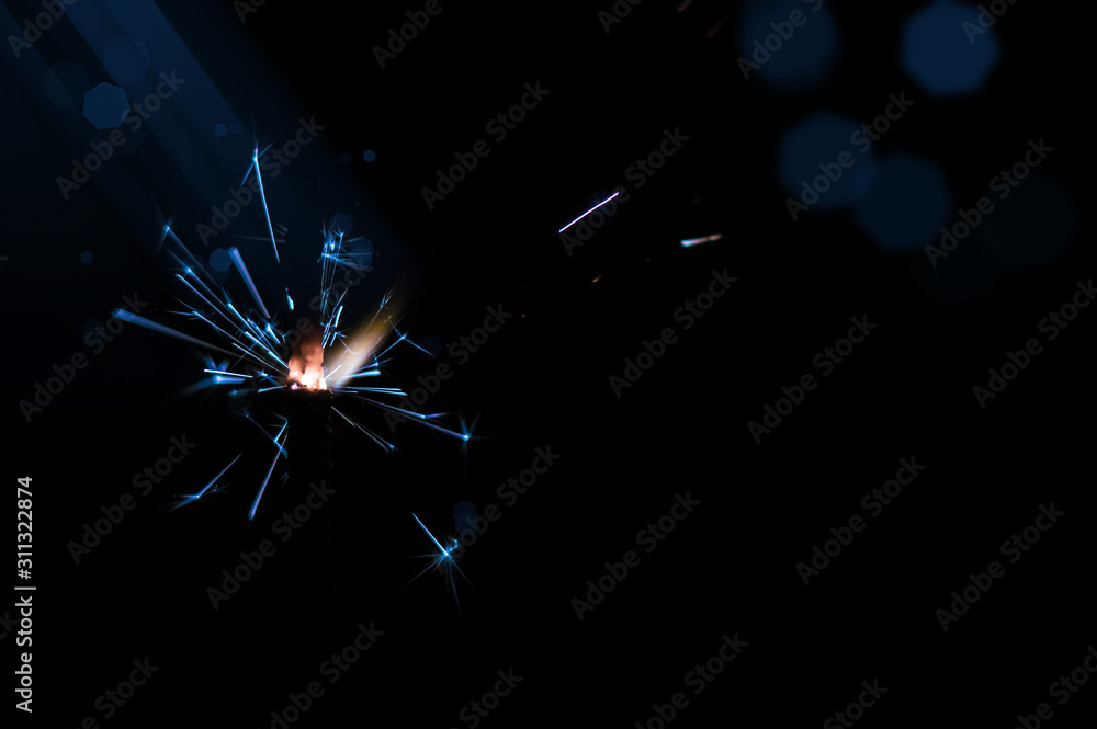Obraz premium Sparkler in blue and white light on a black background