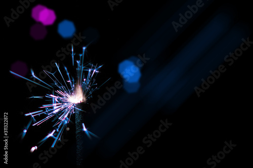 Sparkler in blue and white light on a black background