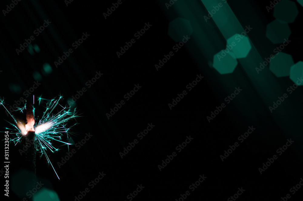 Sparkler in turquoise and white light on a black background. Sparkler in turquoise and white light on a black background.