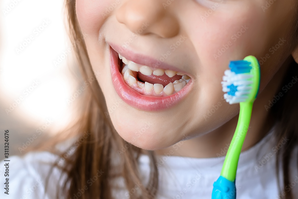 Beautiful smiling preschool girl with her first adult incisor tooth. Cute child showing her baby milk tooth fell out and her growing permanent tooth in open mouth. Dental hygiene concept Beautiful smiling preschool girl with her first adult incisor tooth. Cute child showing her baby milk tooth fell out and her growing permanent tooth in open mouth. Dental hygiene concept