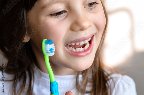 Beautiful smiling preschool girl with her first adult incisor tooth. Cute child showing her baby milk tooth fell out and her growing permanent tooth in open mouth. Dental hygiene concept