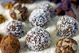Raw Food Candy Balls. Handmade vegan sweets made of almonds, walnuts, dates, coconut and cocoa. Raw food candies in coconut flakes close-up. The concept of healthy vegan sweets, sugarless candie