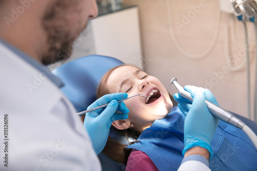 Young caucasian girl calm and happy visiting dentist s office for prevention and treatment of the oral cavity. Child and doctor while checkup teeth. Healthy lifestyle  healthcare and medicine concept.