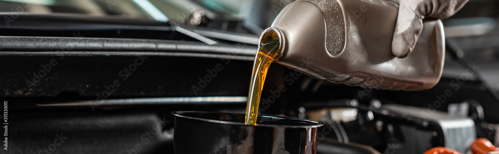 partial view of mechanic pouring machine oil at car engine, panoramic shot - obrazy, fototapety, plakaty 