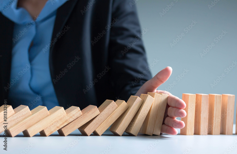 Risk management Businesswoman stop domino effect. leadership has solution for problem.