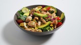 Salad with chicken, avocado, tomatoes, corn, cabbage on a white table