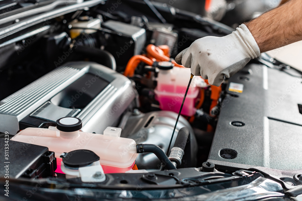 cropped view of mechanic checking engine oil level with dipstick cropped view of mechanic checking engine oil level with dipstick