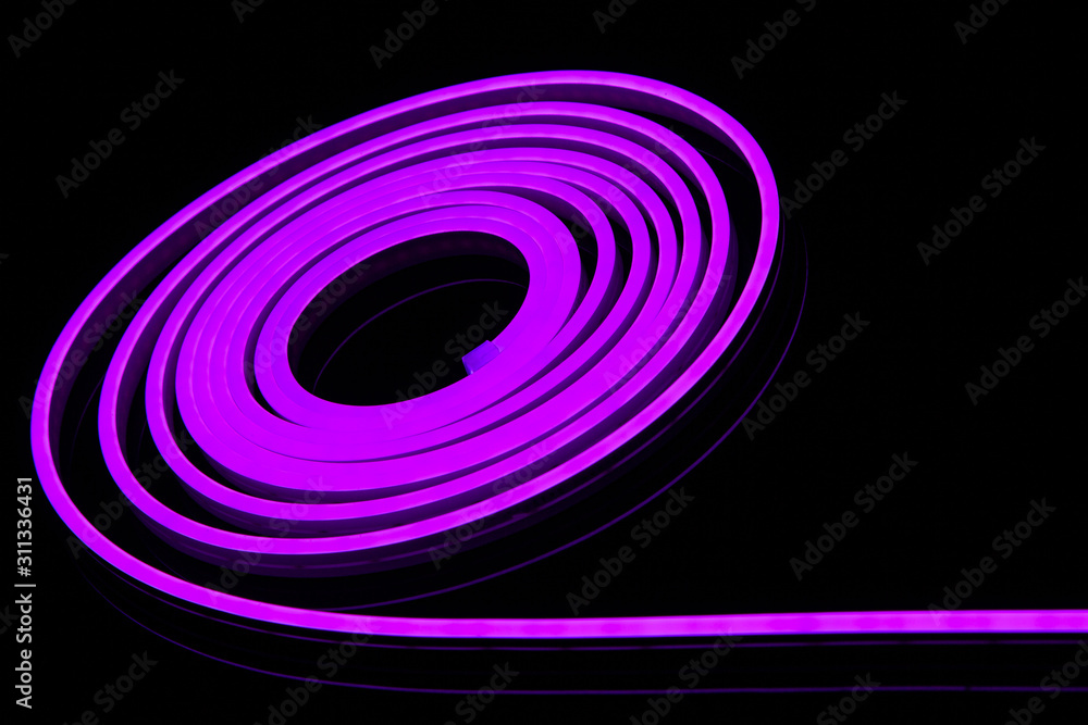 Flexible purple led tape neon flex in roll on black background. Flexible purple led tape neon flex in roll on black background.