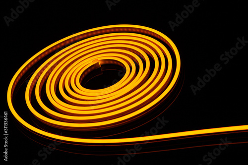 Obraz na plátně Flexible yellow led tape neon flex in roll on black background.