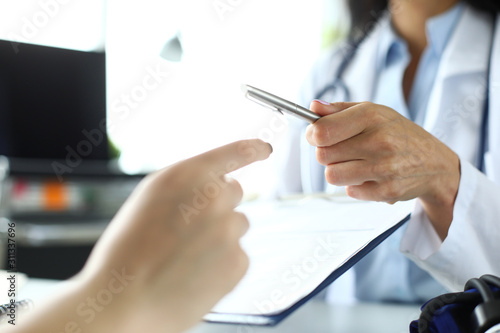 Hand of female GP passing to patient silver pen