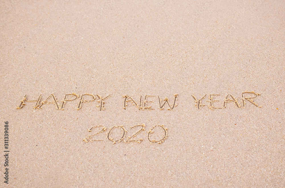 Fototapeta premium Happy New Year's 2020 writing in the sand beach in the morning, appropriate the Backdrop idea copy space