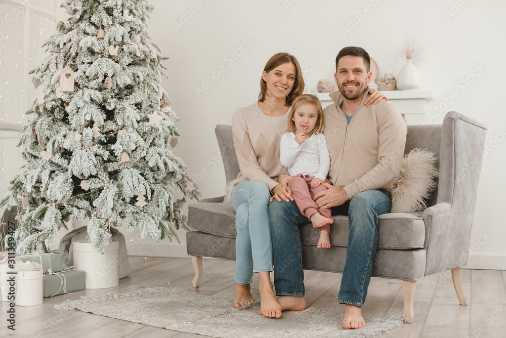 Family Christmas morning in a bright minimalistic living room near the Christmas tree.