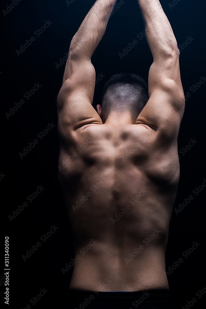 back view of sexy muscular bodybuilder with bare torso posing isolated on black back view of sexy muscular bodybuilder with bare torso posing isolated on black