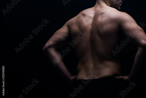partial view of sexy bodybuilder with muscular back posing isolated on black