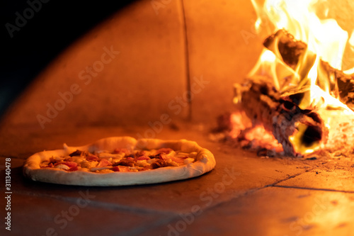 Pizza in the oven near the burning wood
