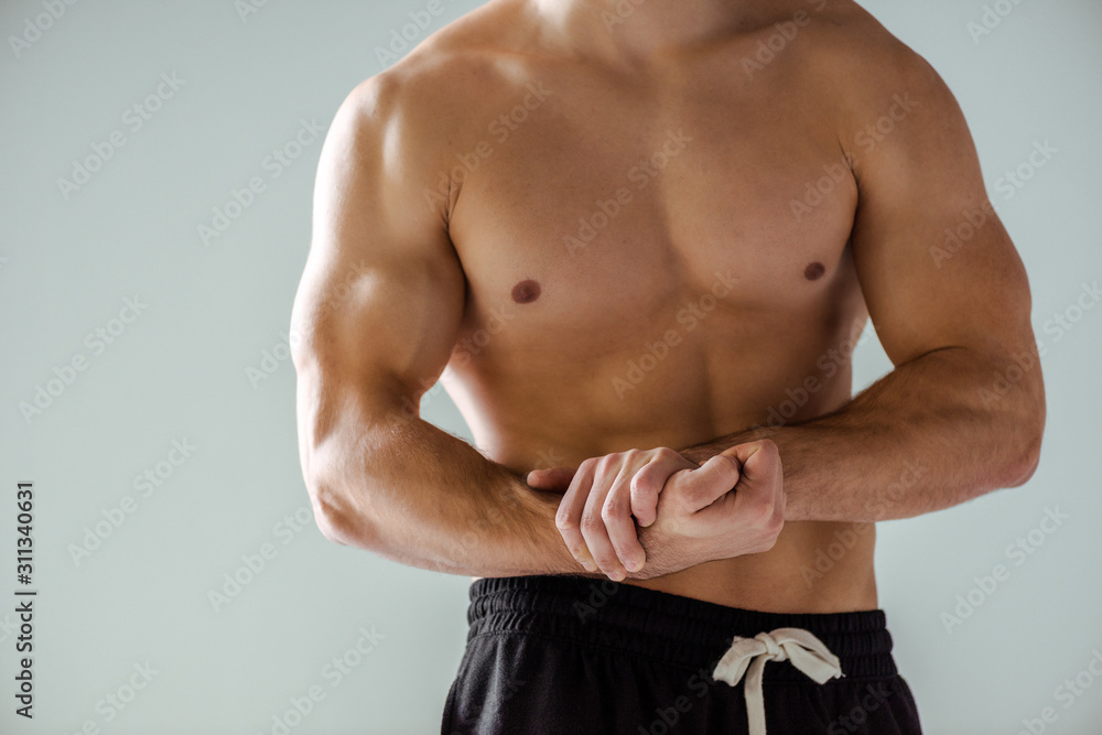 cropped view of sexy muscular bodybuilder with bare torso posing isolated on grey cropped view of sexy muscular bodybuilder with bare torso posing isolated on grey