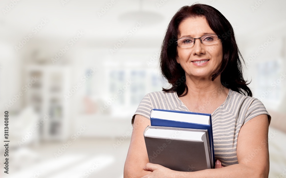 Mature woman teacher with books on background Mature woman teacher with books on background