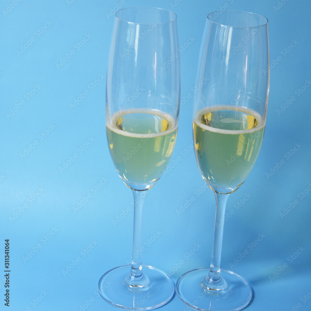 Glasses with champagne stand on a blue background, a yellow lemon lies.
