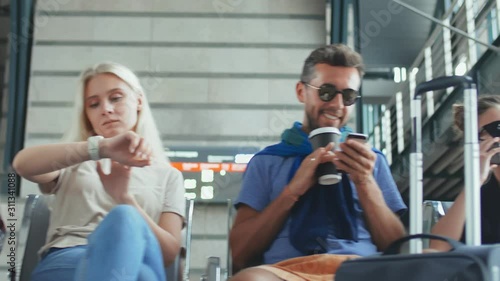 Tourists sitting in airport waiting for hall and using gadgets or drinking coffee waiting for flight.